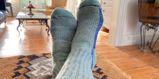 A person has their feet up while wearing light green and blue alpaca socks.