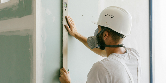 A guy uses a level on a freshly installed piece of drywall