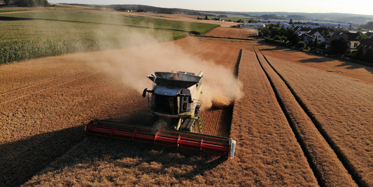 A tractor goes through a field turning over dirt.