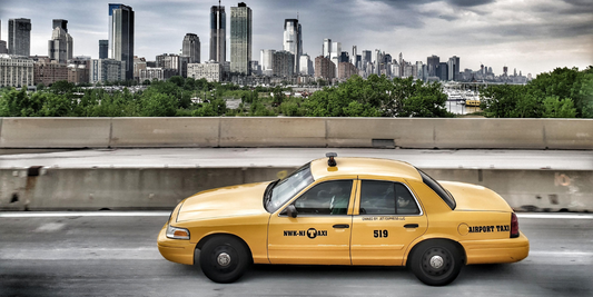 A taxi is pulled over on the side of a bridge with the city in the background.