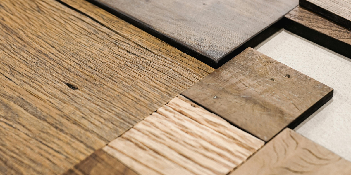 A variety of wood and wood looking tile is laid out on a surface as samples.