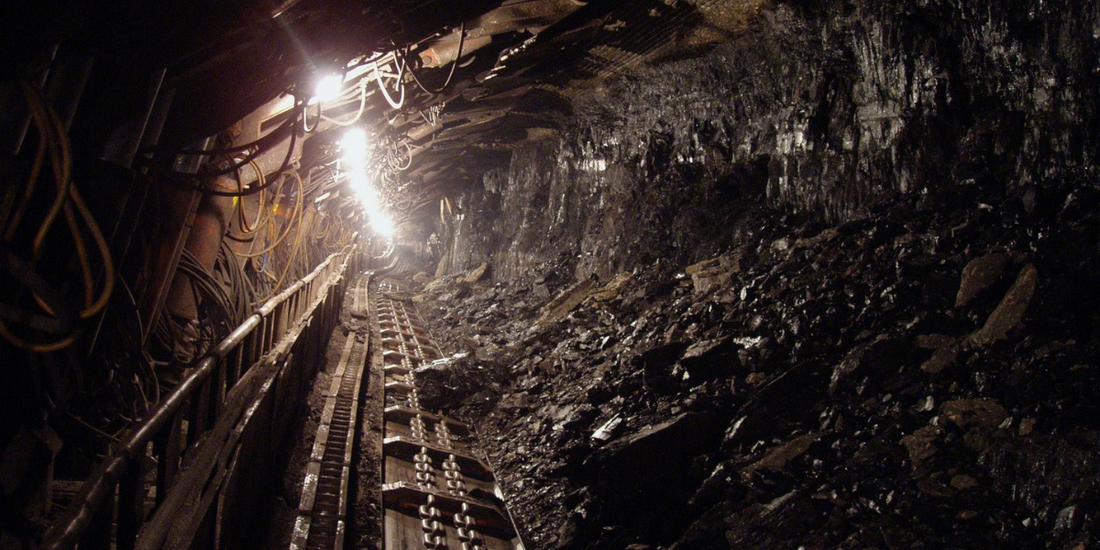 Image of a mine with tracks through it and a light hanging from the top