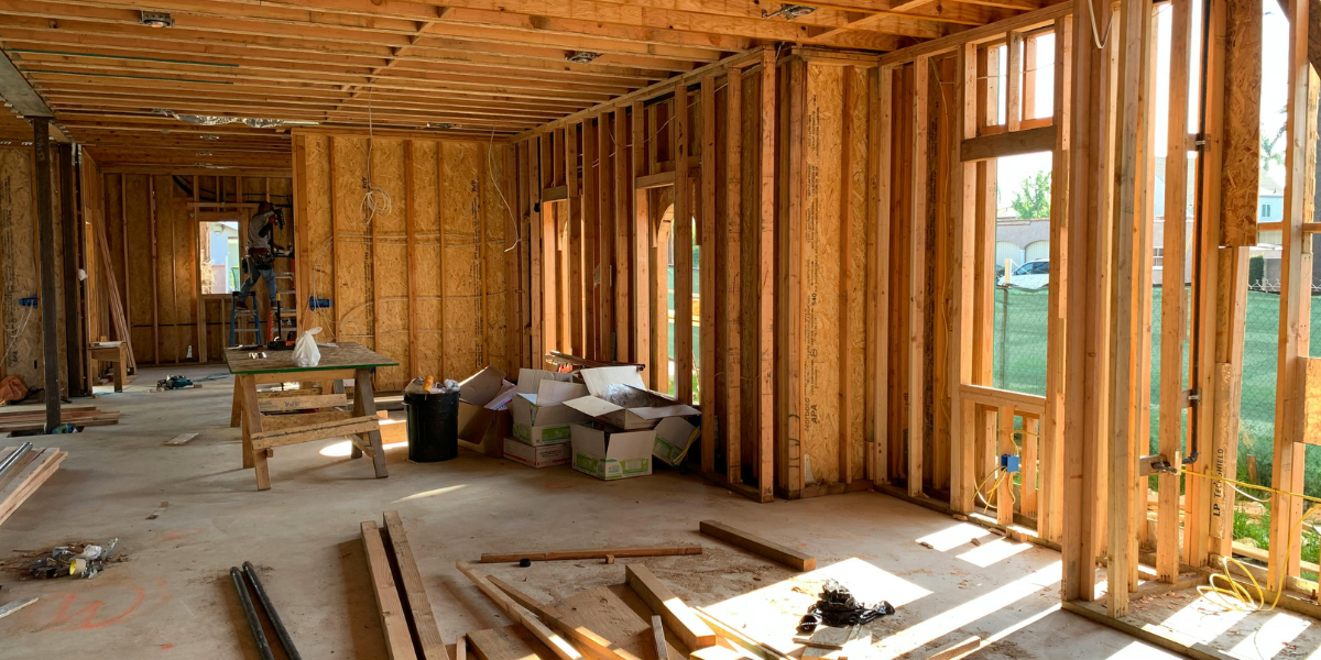 The framing of a house is shown with lumber on the floor.