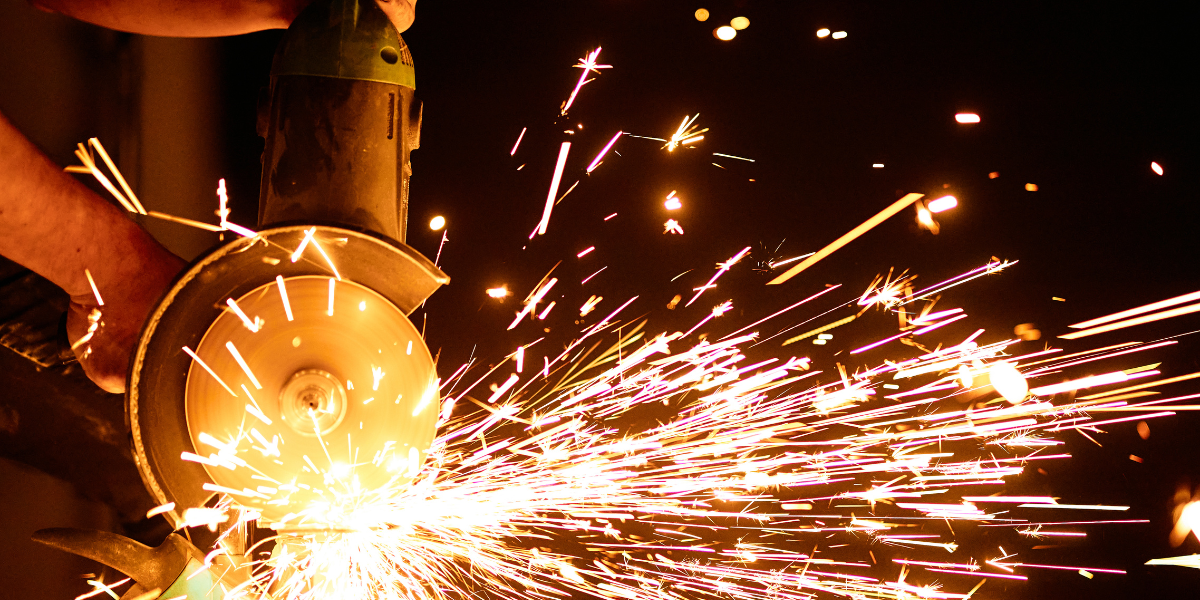 A grinding wheel is being used to cut metal and sparks are flying.