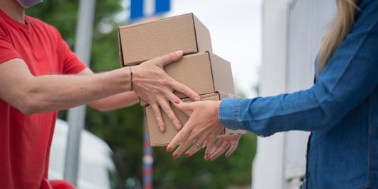 A man in a red shirt hands a lady in a blue shirt 3 small boxes.