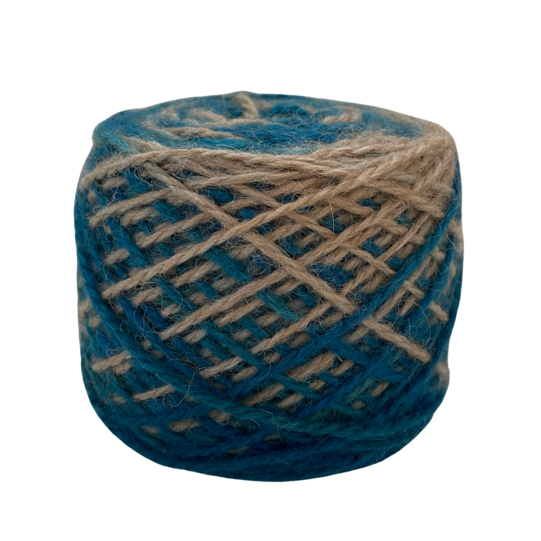 A cake of variegated yarn with alternating stripes of deep teal blue and natural tan, photographed on a solid white background.