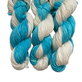 Hand-dyed DK alpaca yarn in blue and cream colors, displayed in a spiral pattern.
