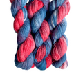A skein of hand-dyed sport weight yarn in red, blue, and white colors.